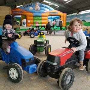 toddlers on pedal tractors and bouncy castle Why is Farmer Palmers Dorset's Favourite Family Day Out!